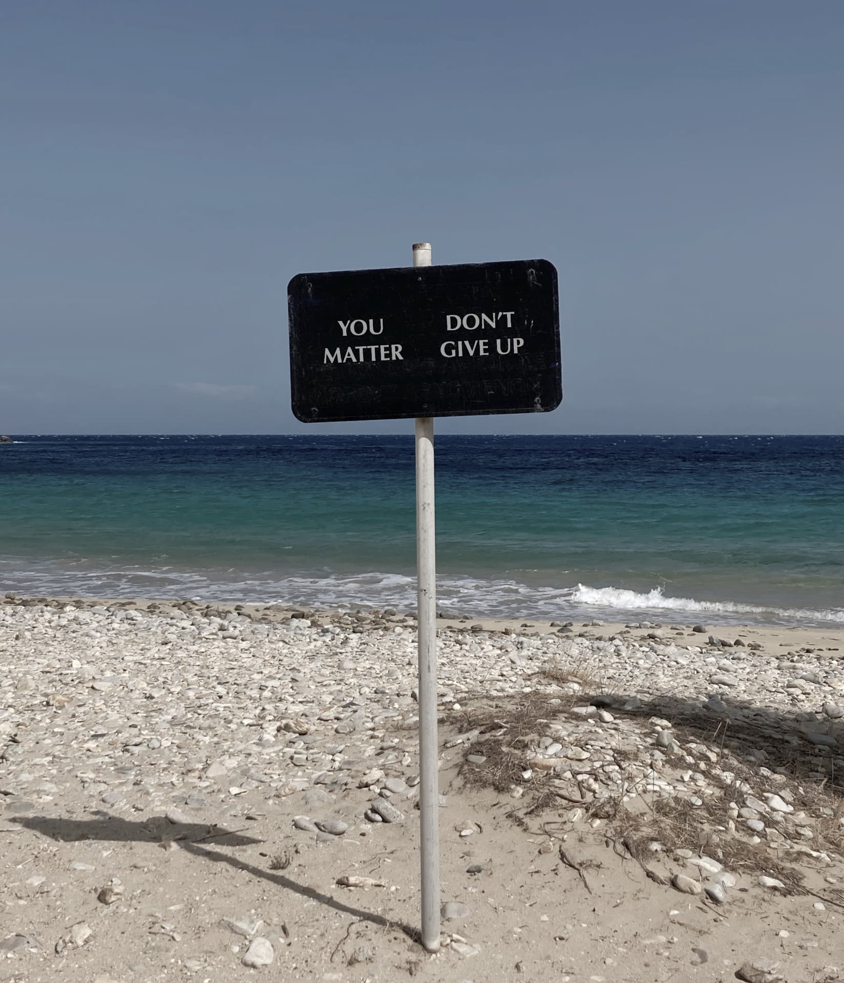 A sign on a Serifos beach reading “You matter — don’t give up”